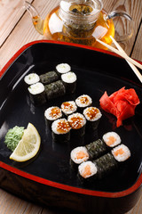 Set of baked sushi rolls with wasabi and ginger on a black background.