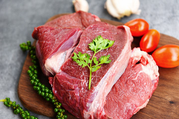 Raw beef meat on wooden cutting board on the kitchen table for cooking beef steak roasted or grilled with ingredients herb and spices Fresh beef animal protein