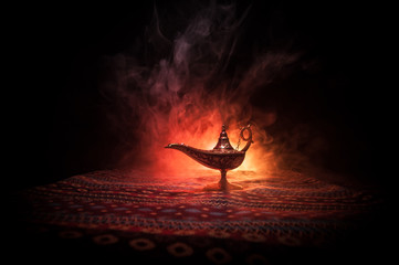 Lamp of wishes concept. Antique Aladdin arabian nights genie style oil lamp with soft light white smoke, Dark background. - obrazy, fototapety, plakaty