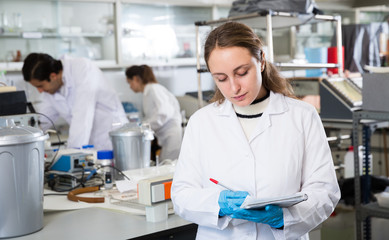 Woman lab technician writing report on chemical experiments