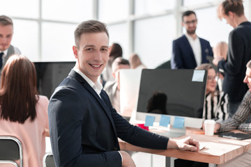 young businessman sitting at his Desk and looking at the camera