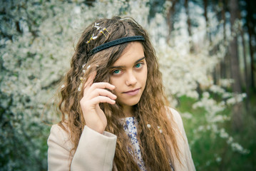 Spring girl in a flowered garden.
Young beautiful girl with long wavy hair in a coat. Portrait of a beautiful girl among blossoming trees. Spring girl in the apricot blossom garden.