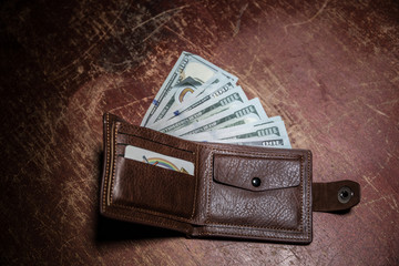 Stylish men's purse with money on wood background.