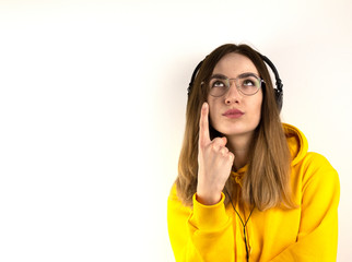 Fototapeta premium Student, a young woman in glasses and headphones shows
