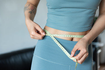 A young Asian woman measures the waist with a ruler