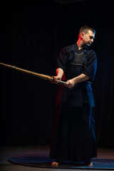 caucasian male kendo fighter in traditional Japanese style of clothing, protective armour, using shinai. practicing fight isolated