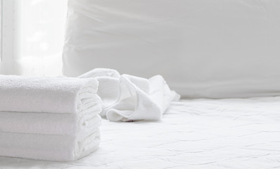 Fototapeta na wymiar Folded clean towels on white bed sheets in bedroom.