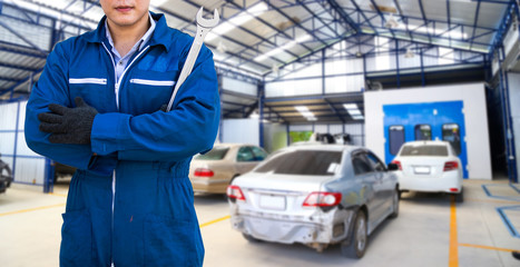 Male engine machanic car service with wrench on hand. blur image of worker fixing car in the garage for background