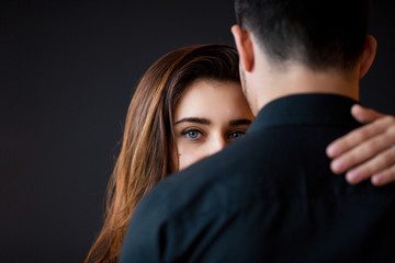 Love and care concept. Beautiful brunette woman with bright eyes looks on her boyfriend. Couple embrace.