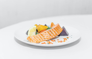 a dish of red fish on a white plate and on white dishes, haute cuisine