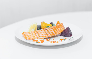 a dish of red fish on a white plate and on white dishes, haute cuisine