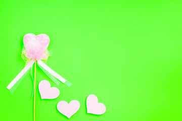 Ein Herz mit Band und drei rosa Herzen vor einem grünen Hintergrund