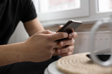 Teenage student surfing the internet using his smart phone