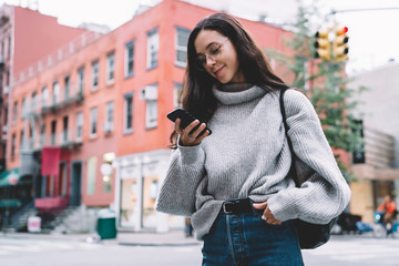 Pleased woman using smartphone on city street