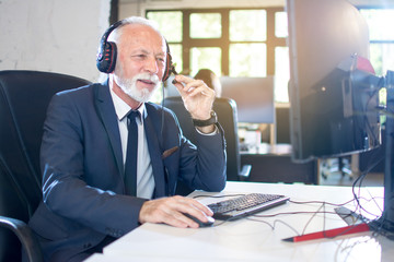 Senior man with headset working on computer in office