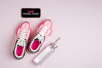 New sneakers and smartphone on a pink background. App for training indoors. Online Fitness program. Home online workout. Top view, flat lay