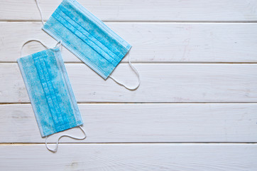 Blue protective medical masks lie on a white wooden table