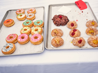 Verschieden dekorierte Donuts auf einem Backblech - obrazy, fototapety, plakaty