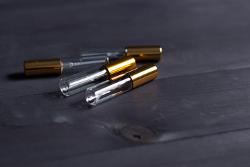 Empty glass and gold parfume vials on black wooden backgroun