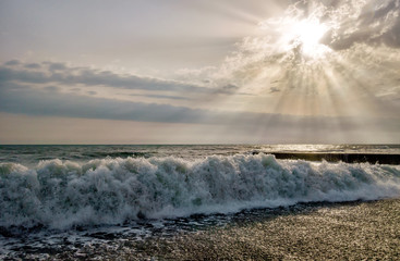 Wave breaking on pebble sea shore at sunset. Scenic landscape at Khosta beach, Sochi, Russia.