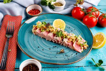 Sliced tuna steak with sesame seeds on a blue plate