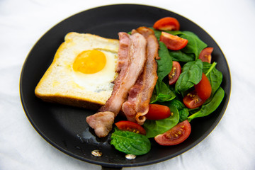 Egg in a hole bread and bacon with salad