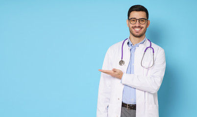 Horizontal banner of smiling young male doctor showing and presenting something with hand, isolated...