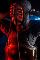 portrait of young Kendo fighter with shinai bamboo sword isolated over smoky space. tradition kendo...