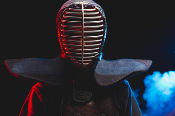 portrait of young Kendo fighter with shinai bamboo sword isolated over smoky space. tradition kendo...