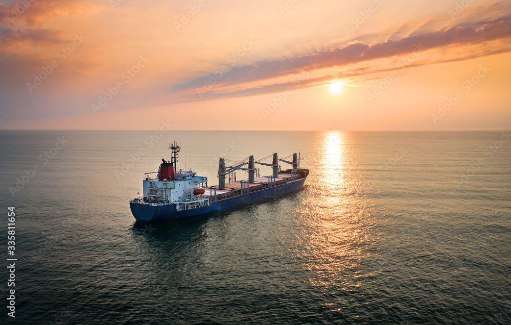 Wall mural cargo ship in the ocean on the sunrise.