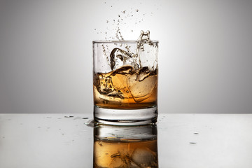 Ice cube falling in a glass of whisky