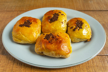 Bolen pisang or banana cake is baked pastry with banana and chocolate filling. In white plate on wooden background