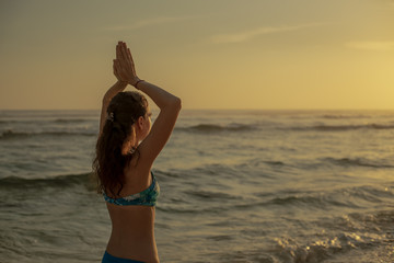 Fototapeta na wymiar Close up of namaste mudra. Young woman raising arms with namaste mudra at the beach. Anti stress. Melasti beach, Bali, Indonesia