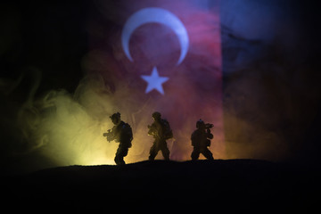 Silhouette of soldier with rifle against a turkish flag. Selective focus