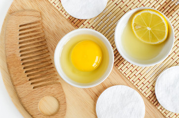Raw egg in the small white bowl, wooden hair brush, lemon juice with lemon slice. Natural homemade...