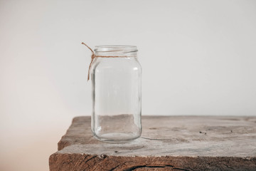 Glass transparent jar on wooden table on white wall background. Copy, empty space for text
