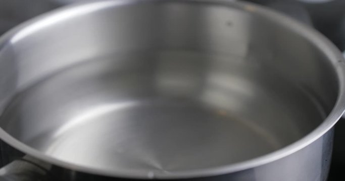 A White Raw Chicken Egg On A Tablespoon Is Placed In Stainless Kitchen Pan With Water To Boil The Egg. Chicken Eggs In Hot Water. Eggs Are Hard Boiled. Cinema 4K Video