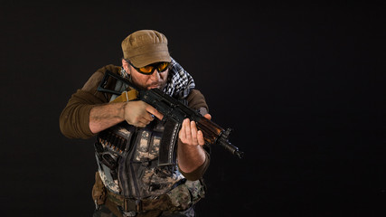 Soldier mercenary with a gun aiming at the enemy. Photo on a dark background.
