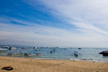 Traditional Balinese fishing boat in the sandy bay at anchor. Sanur, Bali, Indonesia.