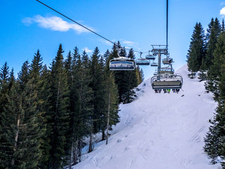 View of coniferous forest and mountains from a chair lift. View of a ski resort piste and Dolomites mountains in Italy from Passo Pordoi pass. Arabba, Italy