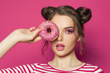 Fashion model woman holding donut on vivid pink background, diet concept