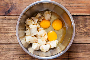 Step by step preparation of banana bread, step 2 - bananas and raw eggs for the dough, top view, selective focus