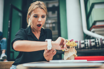 Caucasian woman shocked with received smartwatch notification touching display with expression on...