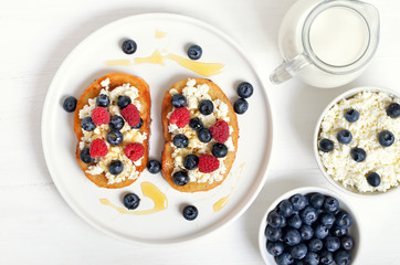 Sandwiches with curd cheese, blueberries, raspberries and honey
