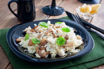 Risotto with chicken and champignons on a black plate, selective focus