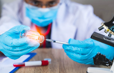 Close up The doctor's hand is holding a bottle of vaccination drugs and using a syringe to suck out the vaccine for the treatment of the virus. infected or infectious concept with blur background.