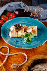 Pancakes with salmon and greenery on a background of blue plates