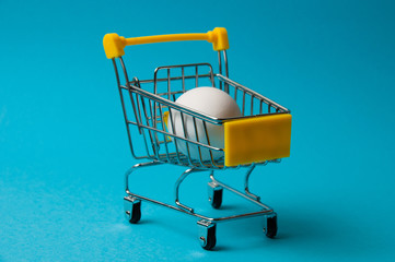 Egg in a yellow grocery cart on a blue background
