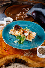 Pancakes with salmon and greenery on a background of blue plates