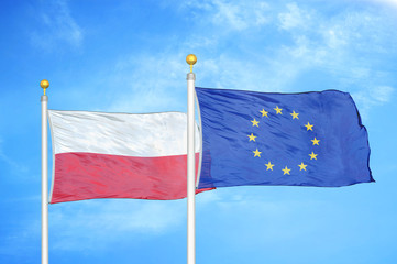 Poland and European Union two flags on flagpoles and blue cloudy sky